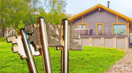 Private house purchase concept emphasizes property access with keys symbolizing ownership of a modern countryside home surrounded by greenery.