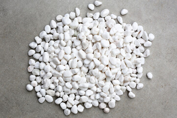 Smooth, white, polished pebbles scattered on a dark black surface.