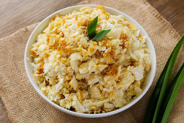 Closeup of a serving of Getuk, a traditional Indonesian sweet dessert made from mashed cassava and topped generously with grated coconut and liquid palm sugar (gula merah). 