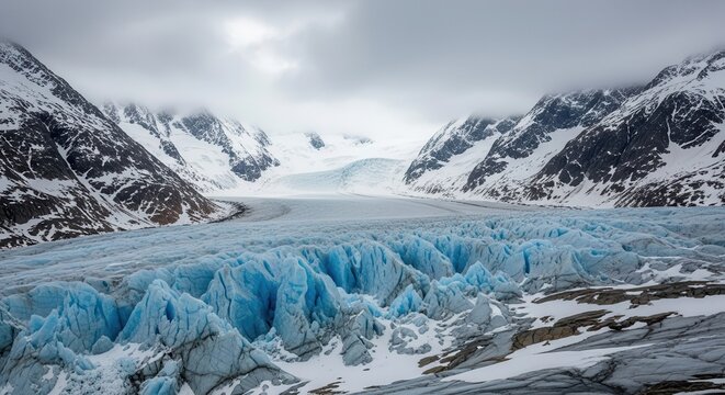 Massive glacial ice flow carves through snow-covered mountain valley under overcast sky - Powered by Adobe