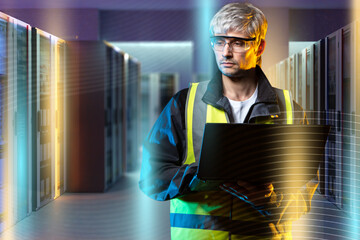 Data center technician monitors server performance using a laptop, ensuring stable operation and maintaining hardware systems in a secure facility.