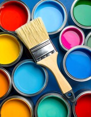 Close-up of open paint cans with a paintbrush, arranged on a blue surface