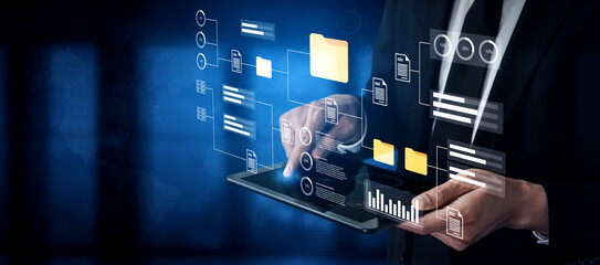 A businessman engages with a digital interface while holding a tablet, showcasing modern technology for data management and analysis in a corporate setting. Gantry