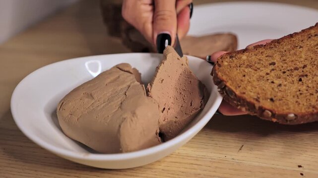 Autumn kitchen with woman spreading thick pork p&acirc;t&eacute; on dark grainy bread
