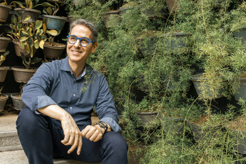 Smiling mature businessman sitting in vertical garden portrait