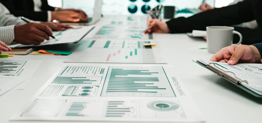 A diverse group of professionals collaborates in a modern office setting, surrounded by charts and graphs, engaging in a strategic business meeting focused on data-driven insights. SACTR