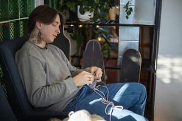 Hipster feminine male crochet handmade knitting hobby with colored yarn and hook at wooden interior
