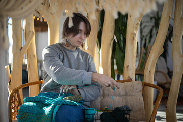 Feminine hipster man crochet handmade use hook knitting needles and wool yarn relaxing on couch