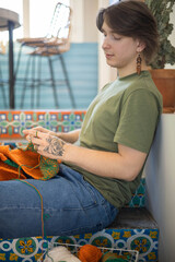 Feminine hipster man crochet handmade use hook knitting needles and wool yarn relaxing on couch