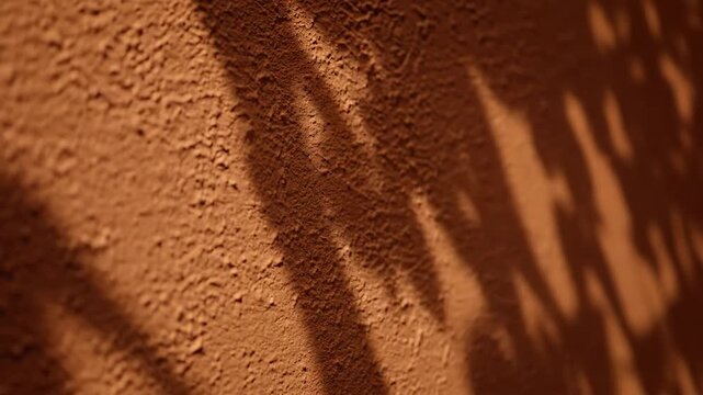 Textured plaster wall background with brown tones, light spot
