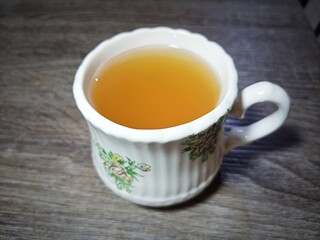 A glass of warm ginger drink is served on the table.