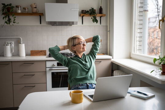 Cheerful middle aged businesswoman leaning back in chair resting arms, feeling satisfied with work done. Relaxed female employee resting from computer screen, looking at window after busy day. - Powered by Adobe