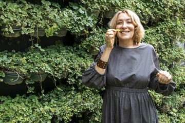 Woman smiling holding fresh leaf at vertical garden