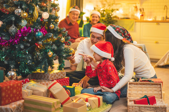 A multi-generation Asian family celebrating Christmas together, decorating the tree and enjoying a warm festive moment. The joyful scene reflects love, togetherness, holiday spirit. - Powered by Adobe