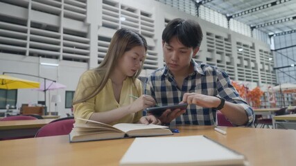 Group of students studying together in library. Two Asian students learning and discussing in a library at the university. - Powered by Adobe