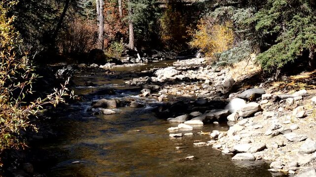 The legendary Pecos River flows over rocks in Pecos River Canyon State Park in autumn in New Mexico
