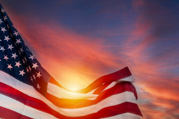 Obraz premium American flag waving with sunlight glowing through stripes against dramatic colorful sky symbolizing pride and freedom