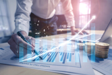 A business professional is analyzing financial growth using charts and currency symbols in a modern office environment. The focus is on strategic improvement. Impute