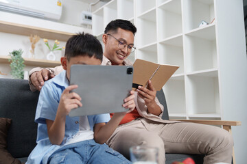 Father and son enjoying digital reading together at home