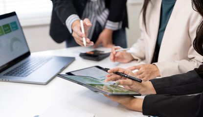 Close-up of business professionals collaborating, pointing at financial data and charts displayed on a digital tablet during an intensive team meeting