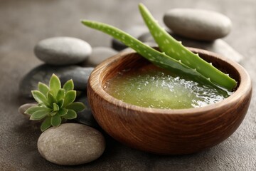 Pure aloe vera gel in a wooden bowl surrounded by smooth stones and succulent plants in a serene spa setting