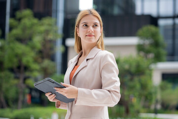 Young caucasian businesswoman reading on digital tablet outdoors in city, executive working with modern technology, communication and corporate lifestyle, business woman working in urban corporate.