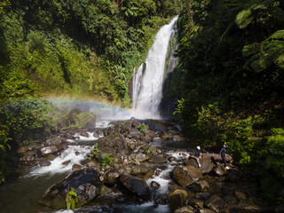 Aerial view of Gomblang Waterfall with Rainbow in Lush Forest, Java Island, Indonesia