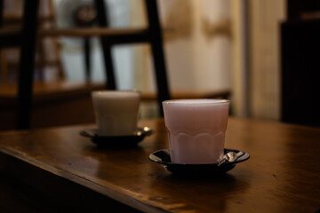 A glass of fresh pink strawberry milk on a wooden table. Sweet creamy dairy beverage served in a cozy cafe.