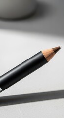 Sharpened cosmetic pencil with a brown tip rests on a bright surface