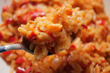 Cooking orzo with red sauce and peppers on a spoon
