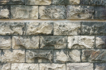Close-up texture of a decorative split-face stone wall with a rugged and uneven natural pattern.