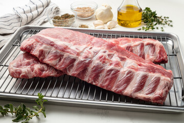 Medium shot of raw rib steak on a metal rack with prop ingredients in the background.  © Mia's Stock