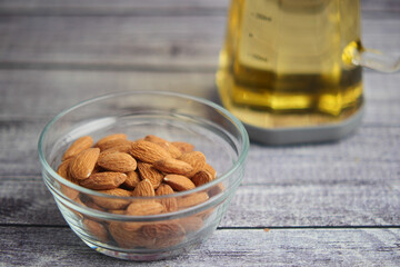 Bowl of almonds beside a bottle of oil on a wooden table
