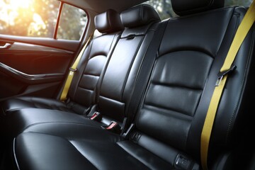 Obraz premium Modern car interior featuring sleek black leather seats and safety belts in a stylish setting with warm sunlight streaming through the windows