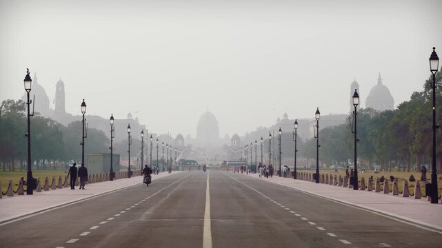 Delhi, India, November 28, 2025. Morning view of Kartavya Path with pedestrians and light traffic leading toward Rashtrapati Bhavan under hazy winter skies.