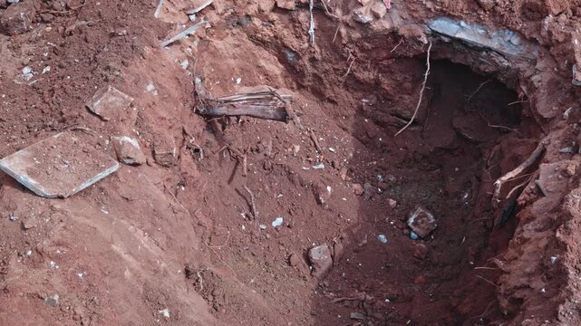 JCB Back hole bucket lifting red soil from hole. day time, stable shot, 4k.