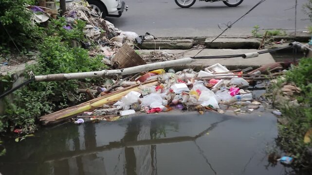 Plastic waste clogs a roadside drain in a city. Footage taken in Java, Indonesia, on December 7, 2025.
