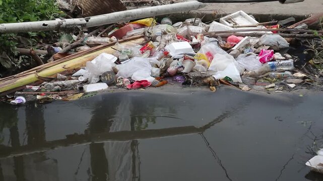 Plastic waste clogs a roadside drain in a city. Footage taken in Java, Indonesia, on December 7, 2025.