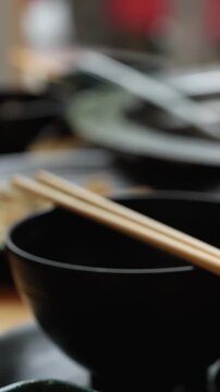 Chopsticks Resting on Black Bowls at Hotpot Table