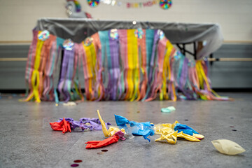Close up of deflated colorful balloons on floor after birthday party celebration.
