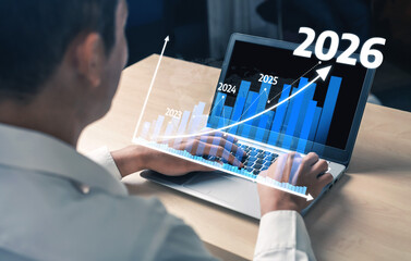 A business professional is engaged in data analysis on a laptop, showcasing projections for growth from 2022 to 2026. The upward graphic symbolizes success. Tessel © InfiniteFlow