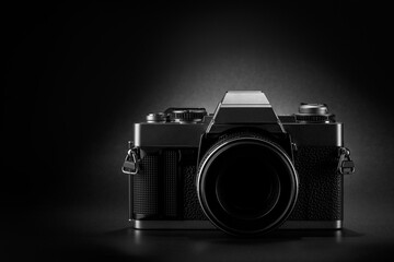 Metal DSLR camera silhouette on dark matte background with copy space.