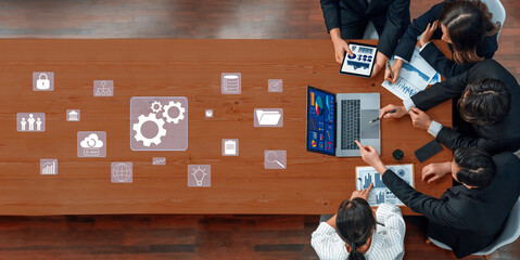 A diverse business team engages in collaborative data analysis and strategy planning, utilizing technology and creative ideas at a stylish wooden desk. Trope