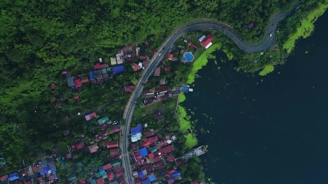 A top-view aerial of winding road and hillside homes along the forested edge of Taal Lake in Talisay, Batangas, Philippines
