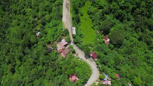A rotating pull-out aerial of a curving road near People's Park in the Sky with a hillside huts in Tagaytay, Cavite, Philippines
