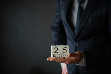 Portrait of  businessman ready for Christmas. Wooden cubes with inscription 25 december