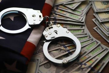Handcuffs on American Flag with Hundred Dollar Bills Depicting Crime and Legal Consequences