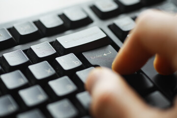 Close-Up Hand Typing Enter Key on Black Computer Keyboard for Technology and Communication Concept