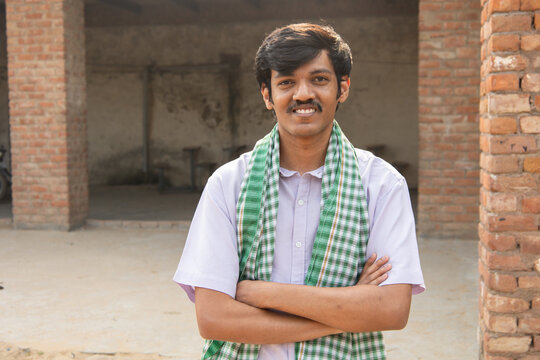 Confident young rural indian farmer or labor standing arms crossed. Smiling conman man looking at camera. People of india.