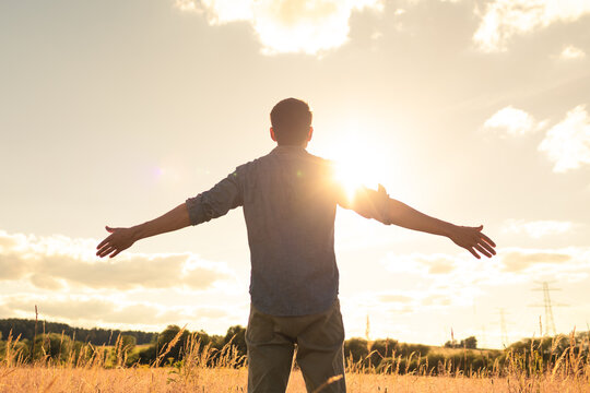 Man Embracing the Sun at Sunset in Open Field &ndash; Freedom and Peace Concept